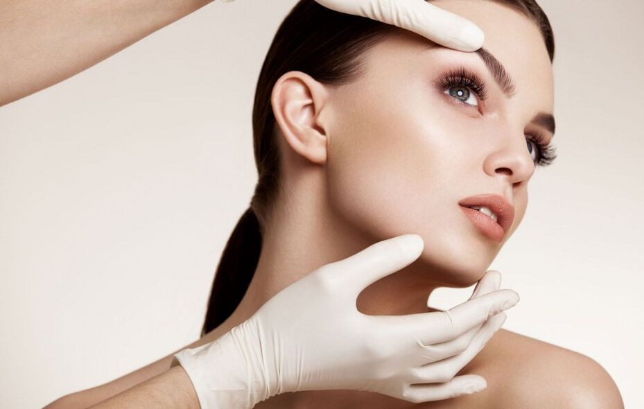 The cosmetologist examines the facial skin before rejuvenation